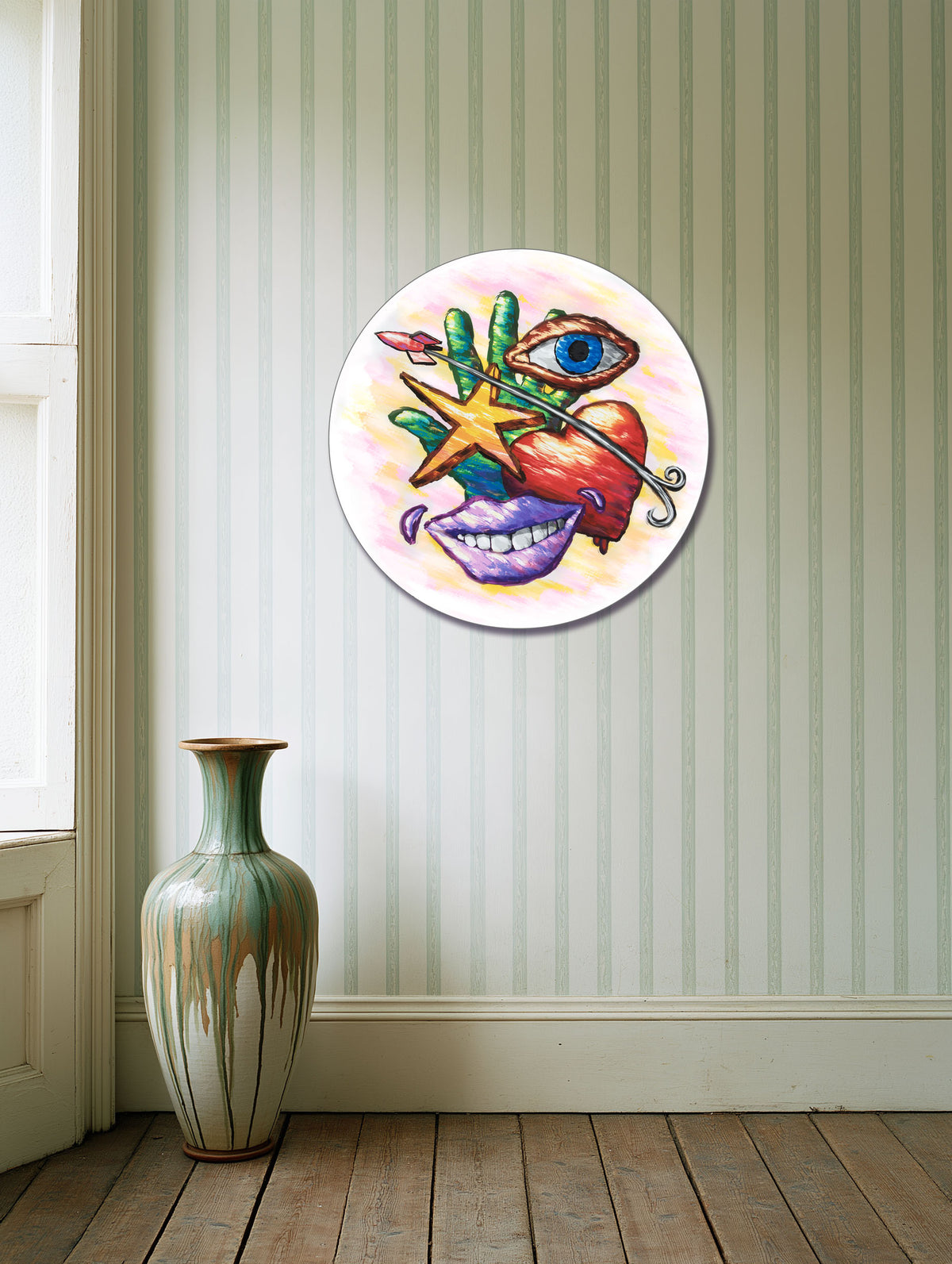 Hand Eye Heart Mouth Star round canvas print on a striped wall beside a decorative vase